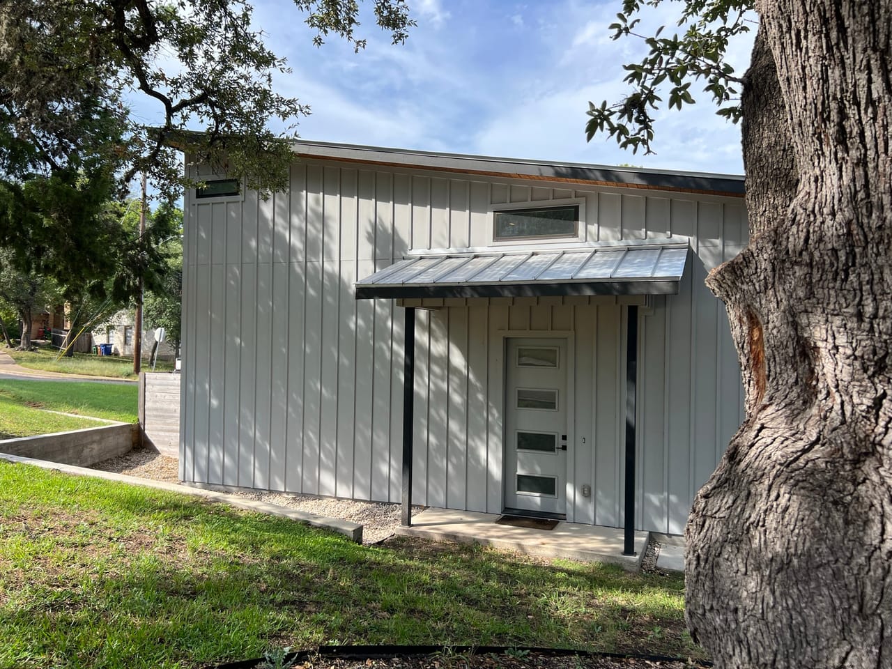 Building exterior with mowed lawn, oak tree and sidewalk in Central Texas