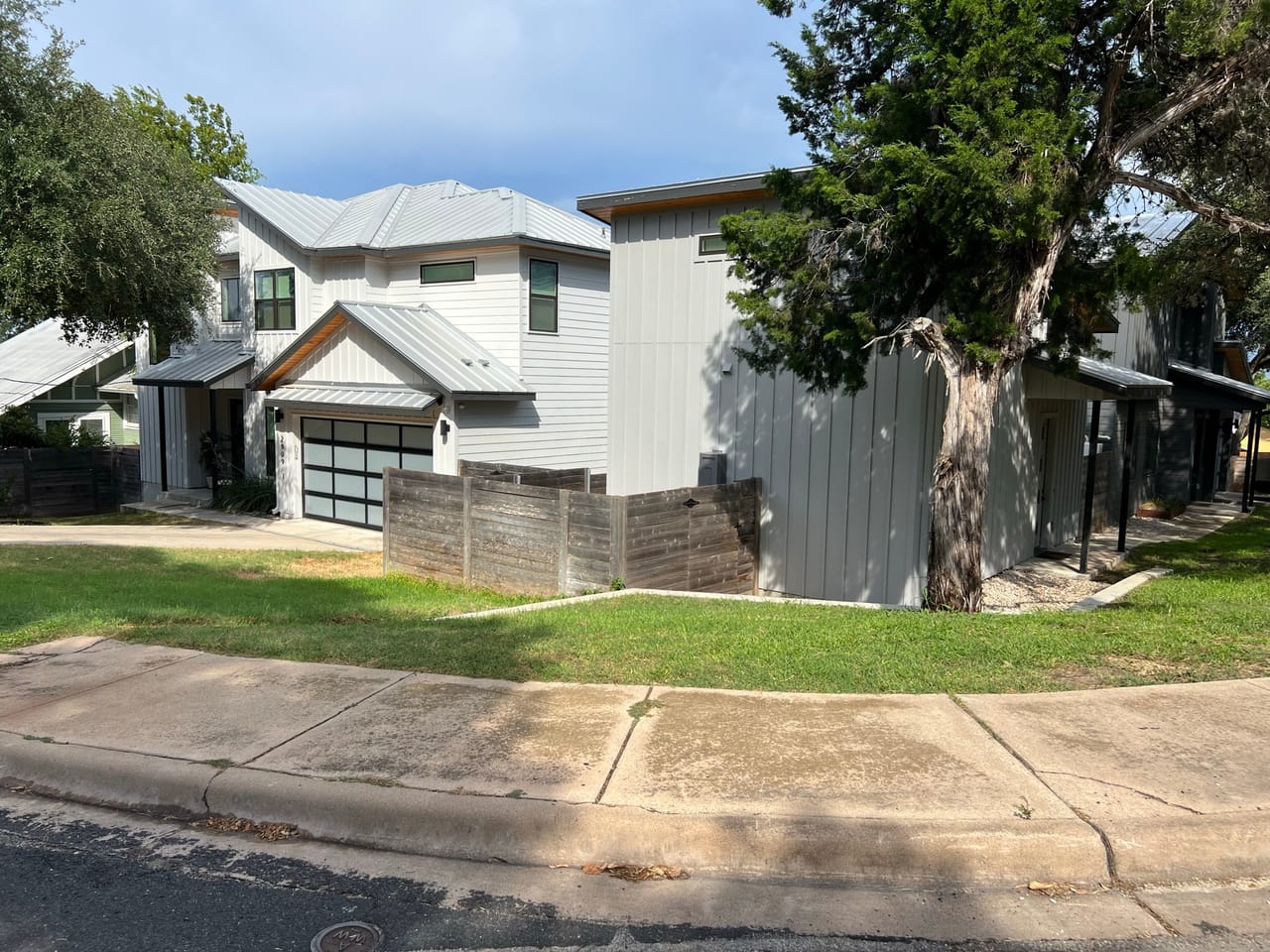 Corner street view of homes with mowed lawn and oaks in Central Texas
