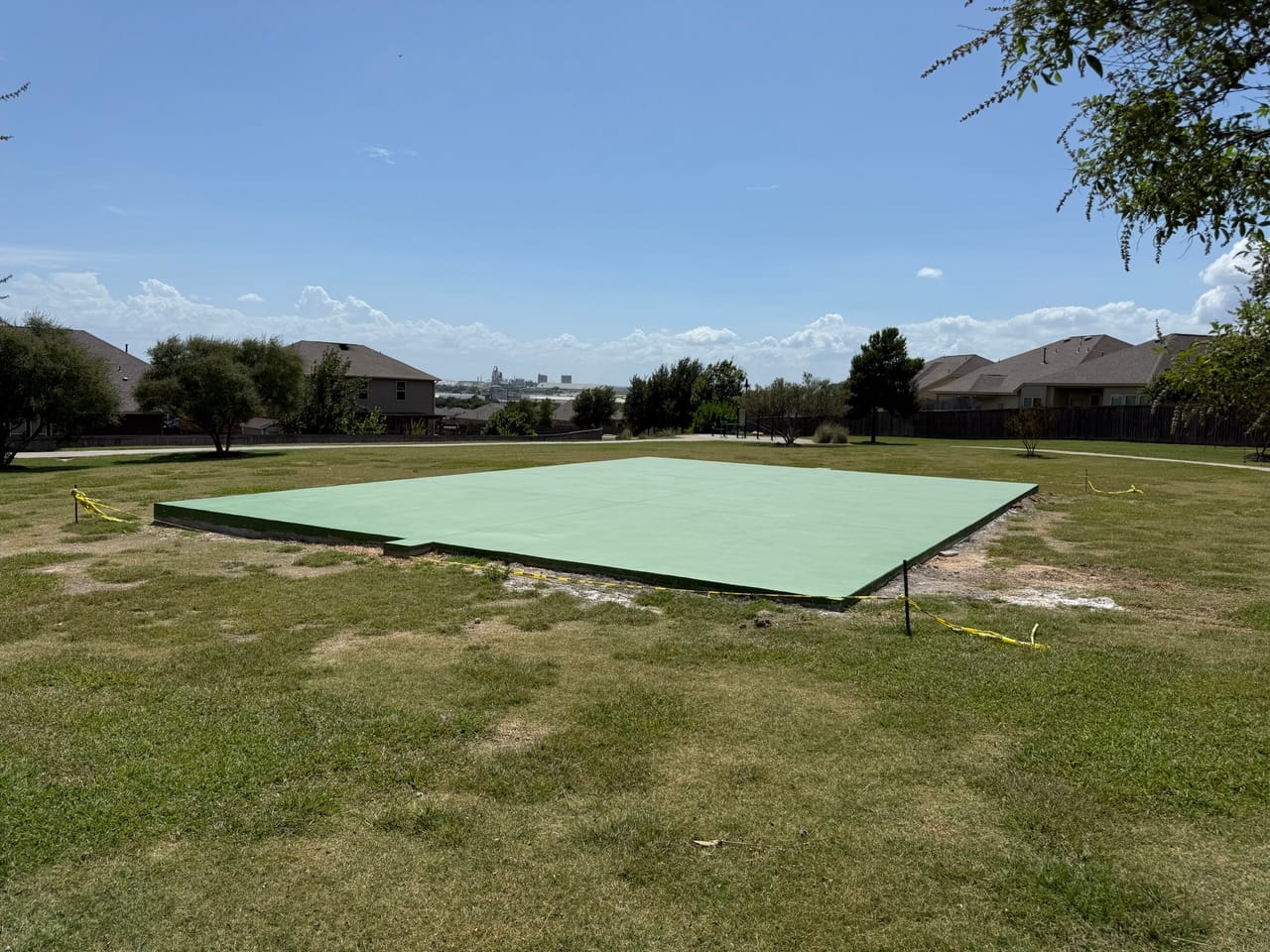 Green painted concrete sport court pad in an open grassy park in Round Rock, TX