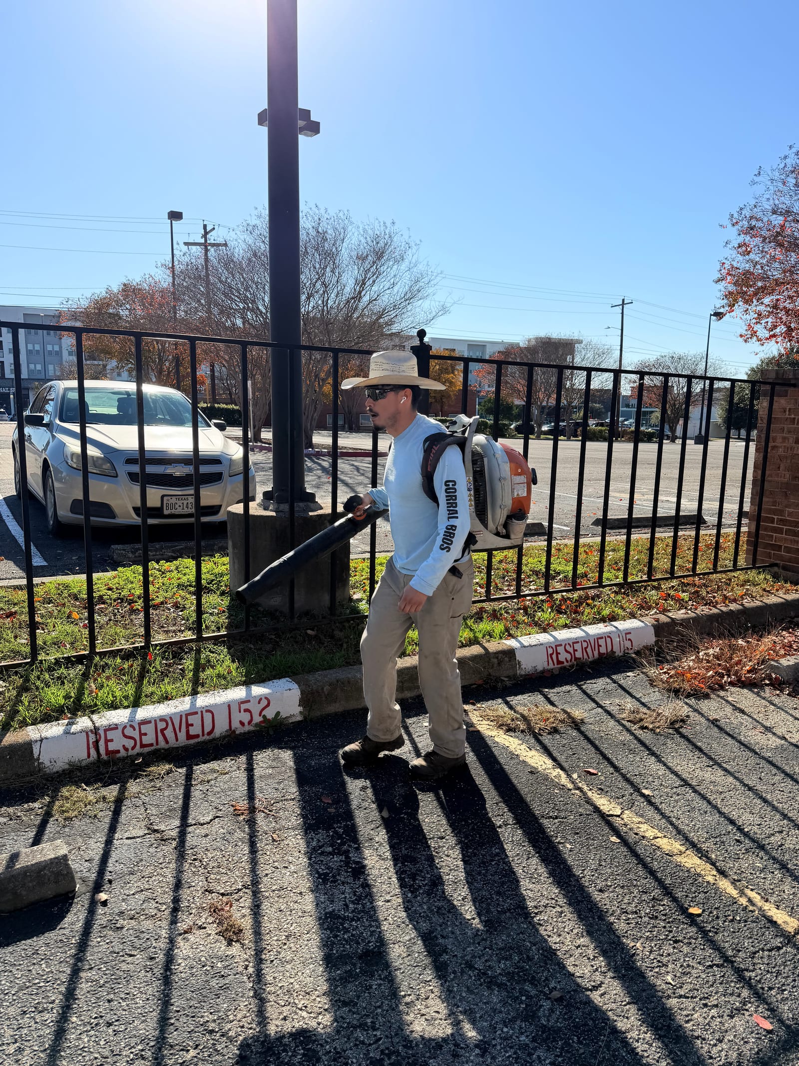 Corral Bros crew member clearing leaves with a backpack blower on a Central Texas commercial property