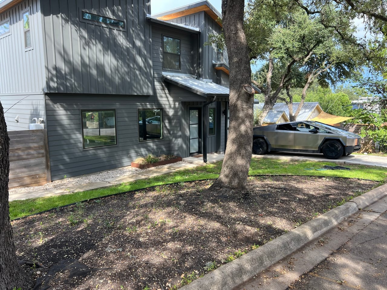 Modern building with fresh mulch bed under a large oak in Central Texas