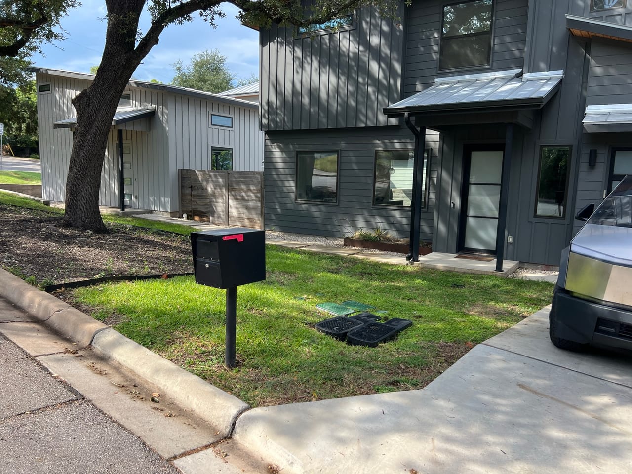 Modern gray townhome exterior with small mowed lawn and mailbox in Kyle, TX