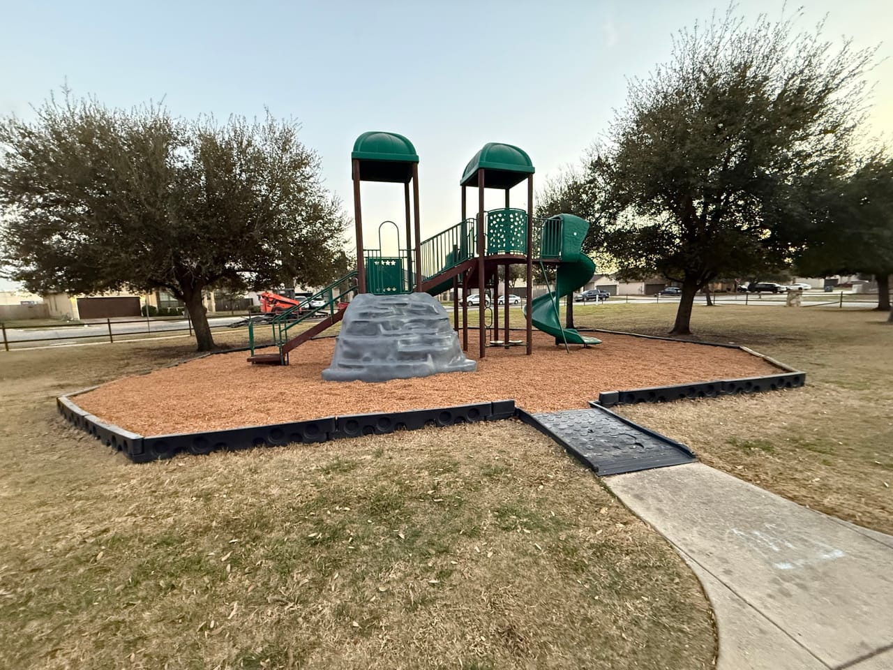 Park playground with fresh mulch bed and stone retaining edge in Leander, TX