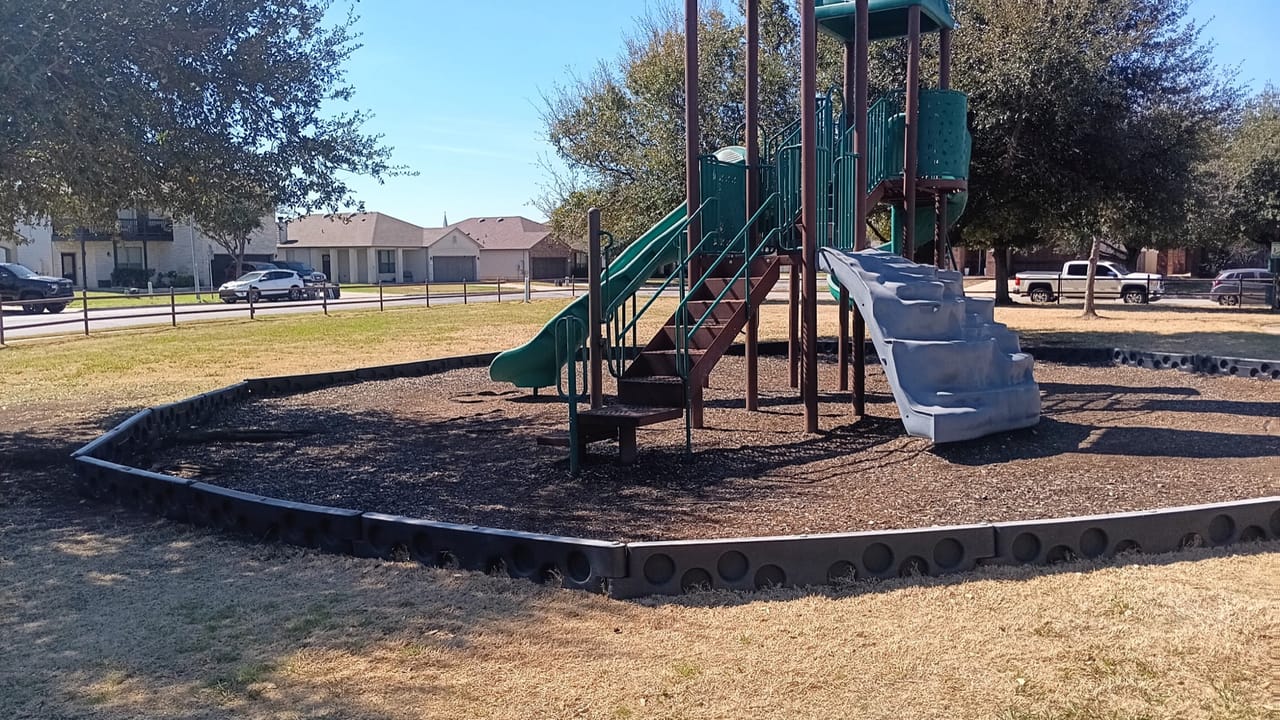 Playground structure surrounded by fresh mulch and clean bed edging in Central Texas
