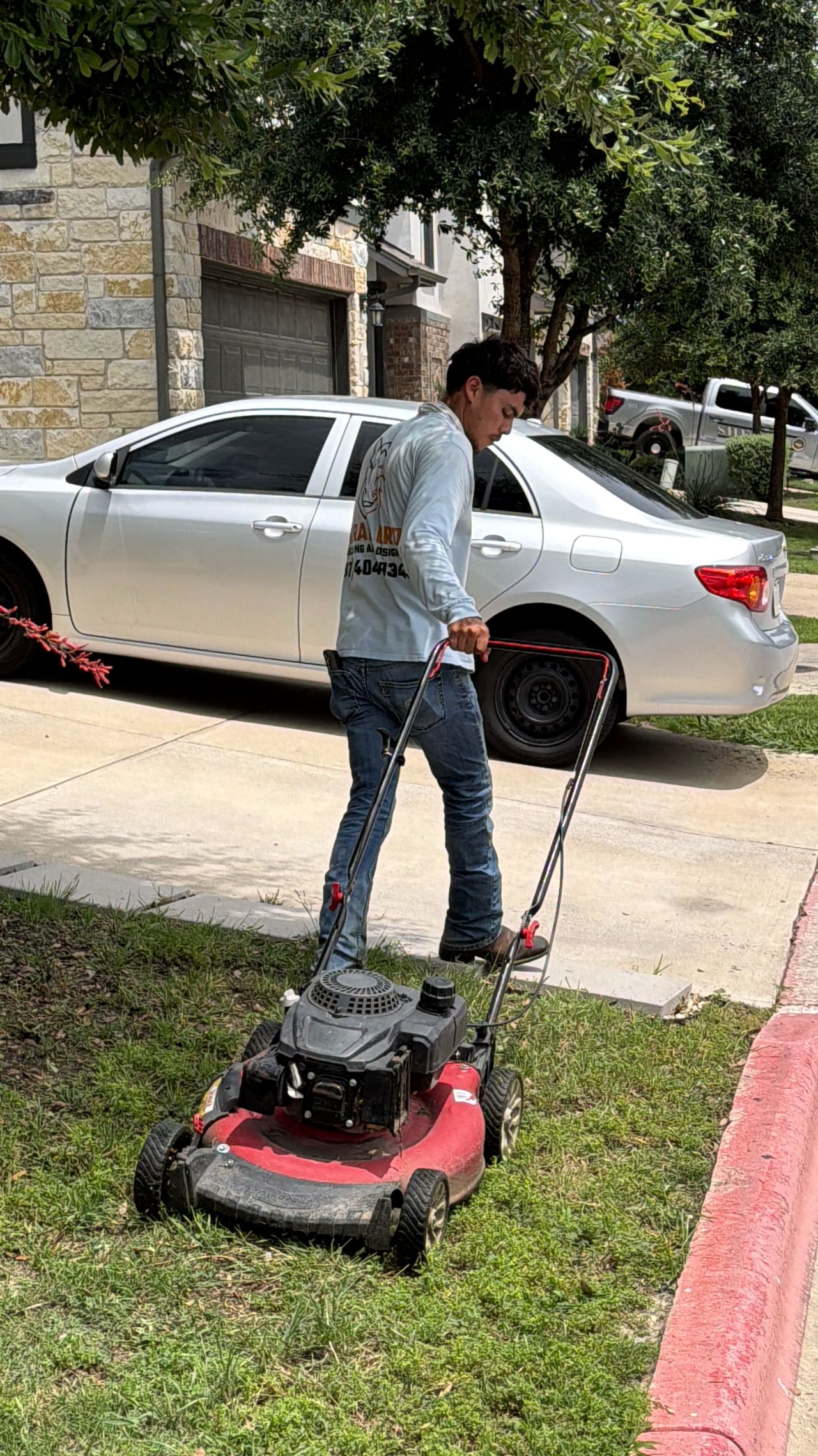 Corral Bros lawn maintenance crew in branded shirt mowing in Austin