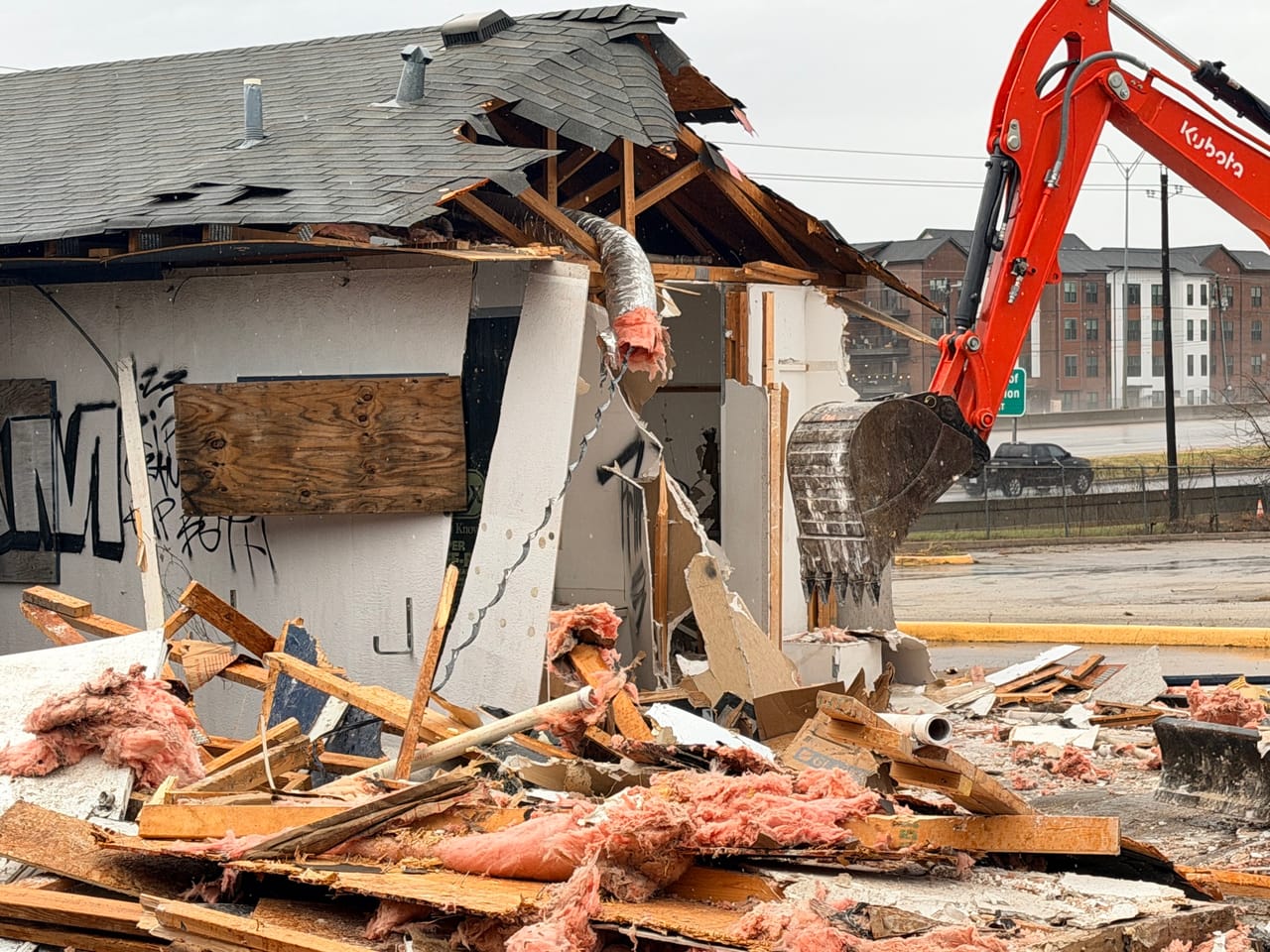 Kubota excavator tearing the roof off a boarded up stucco building in Leander, TX