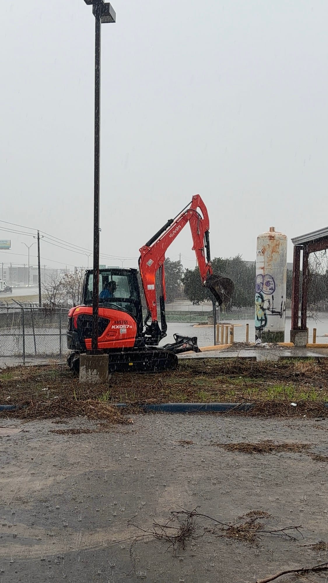 Kubota excavator working a cleared demolition site under a gray sky in Kyle, TX