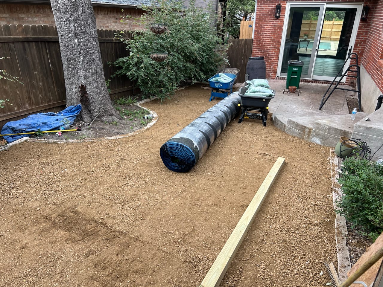 Backyard dirt prep with coiled corrugated drain pipe near the patio in Kyle, TX