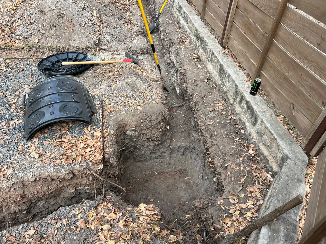 Black catch basin set in a trench beside a concrete curb in Central Texas