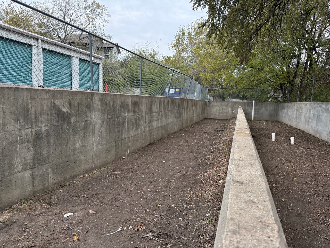 Clean sloped concrete channel running between walls after debris removal in Buda, TX