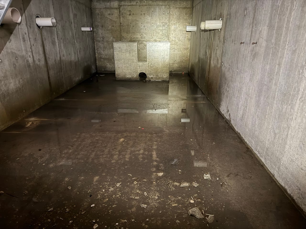 Concrete stormwater vault interior with outlet pipes and a damp floor in Bee Cave, TX
