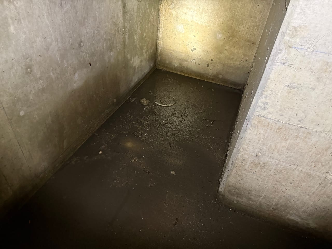 Concrete stormwater vault interior with shallow water and a baffle wall in Manor, TX