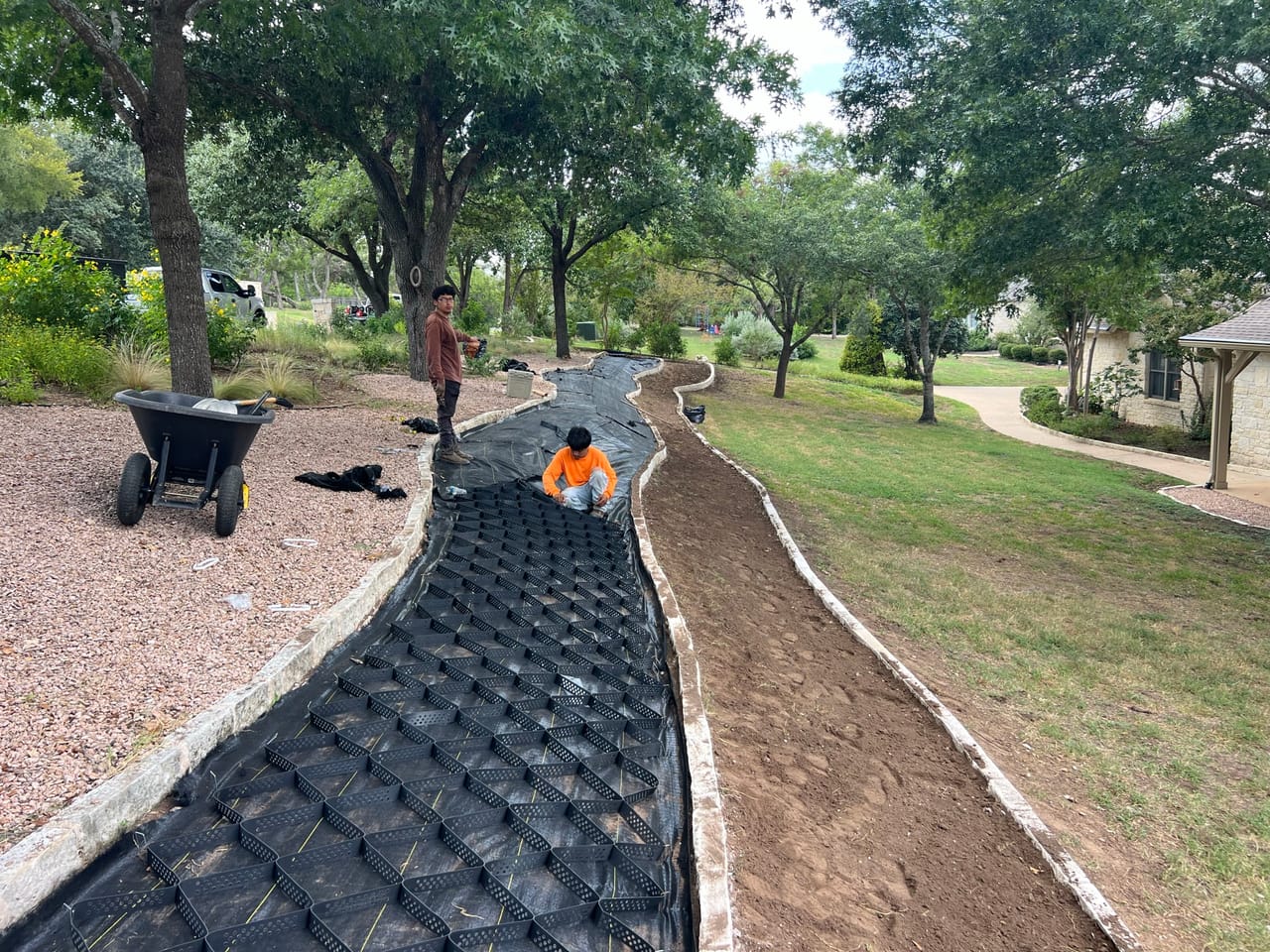 Crew installing geocell matting in a long swale along a street in Lockhart, TX