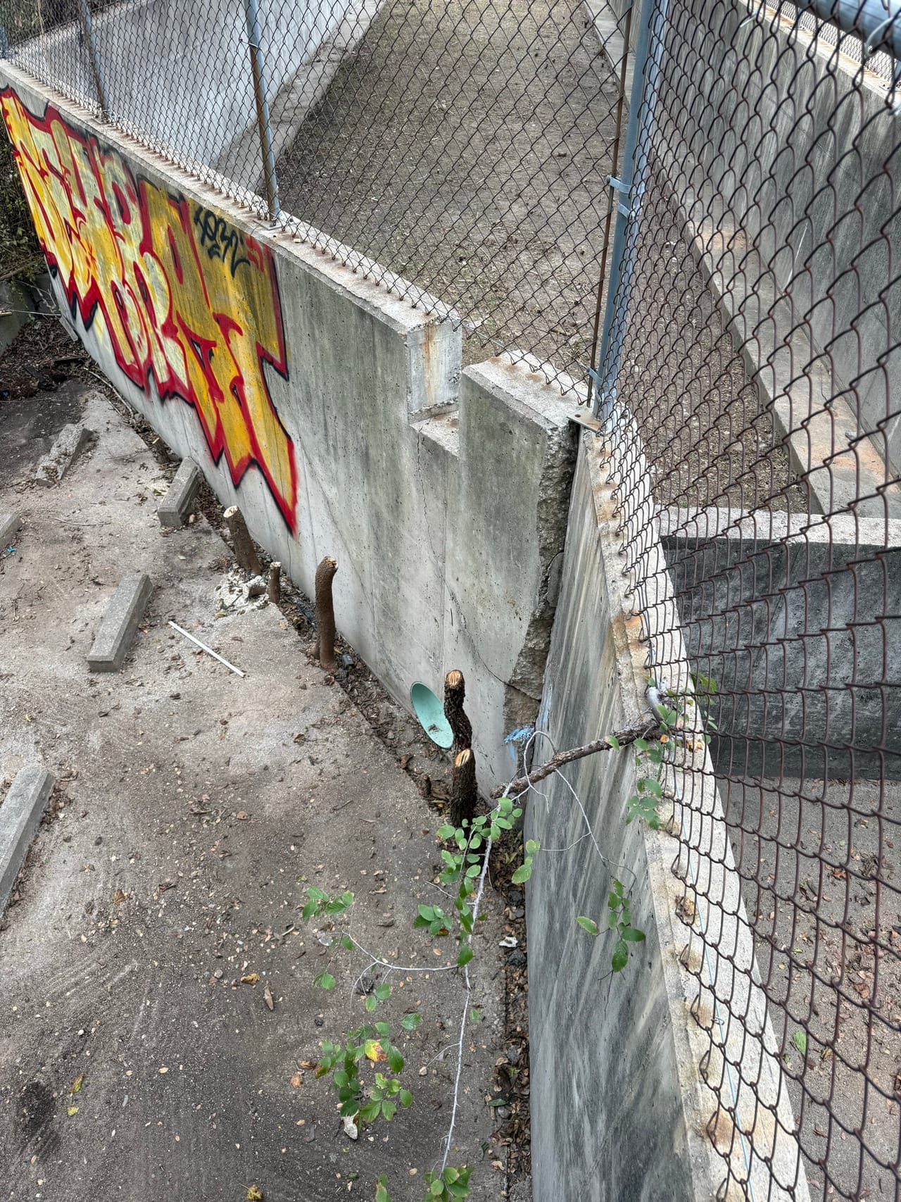 Debris and graffiti inside a wide concrete flume being cleared in Pflugerville, TX