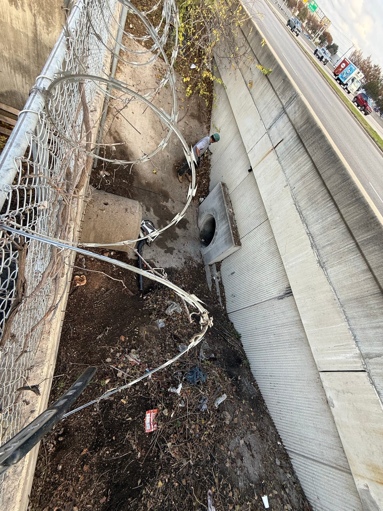 Debris and loose wire fencing inside a concrete channel under bridge in Austin, TX