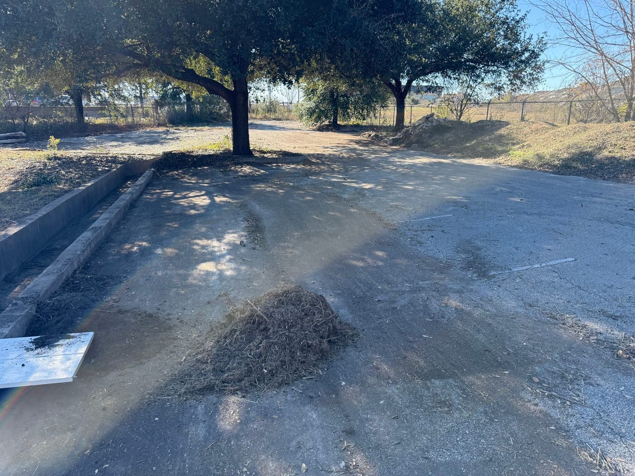 Dirt swale with mounded spoil piles cut through a commercial lot in Central Texas