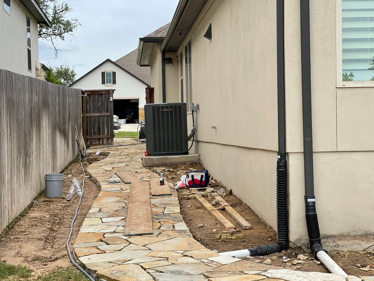 Flagstone path in progress with drain pipe trenches beside the AC unit in Georgetown, TX