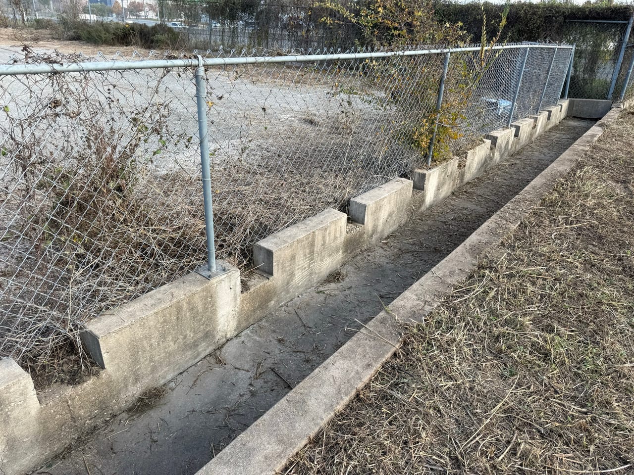 Long concrete drainage channel cleaned out along a chain link fence in Leander, TX