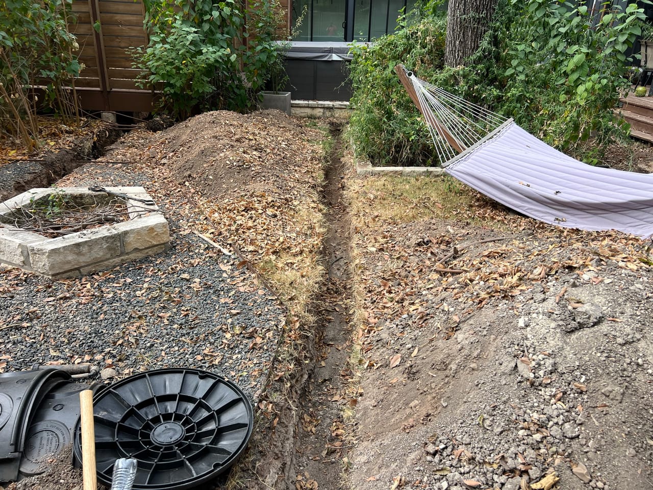 Mound of soil with a black drain basin in a backyard in Taylor, TX