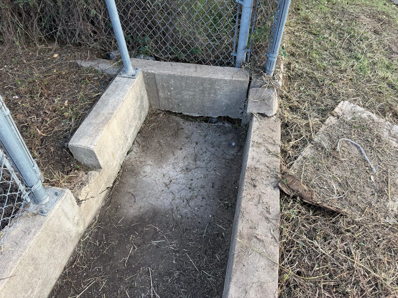 Narrow concrete channel section swept clean between fence posts and brush in Lakeway, TX