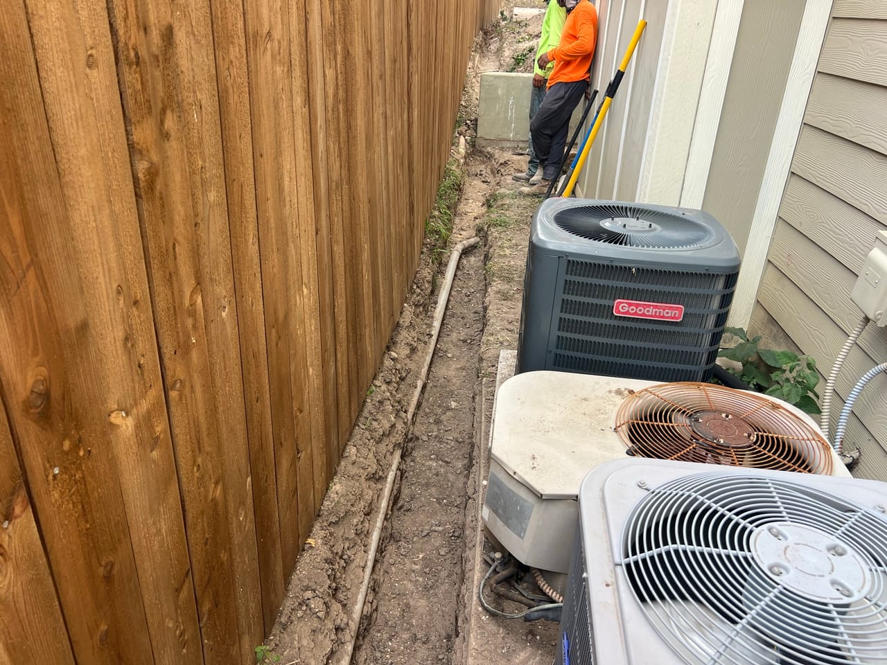 Narrow trench along a wood fence next to an AC condenser in Austin, TX