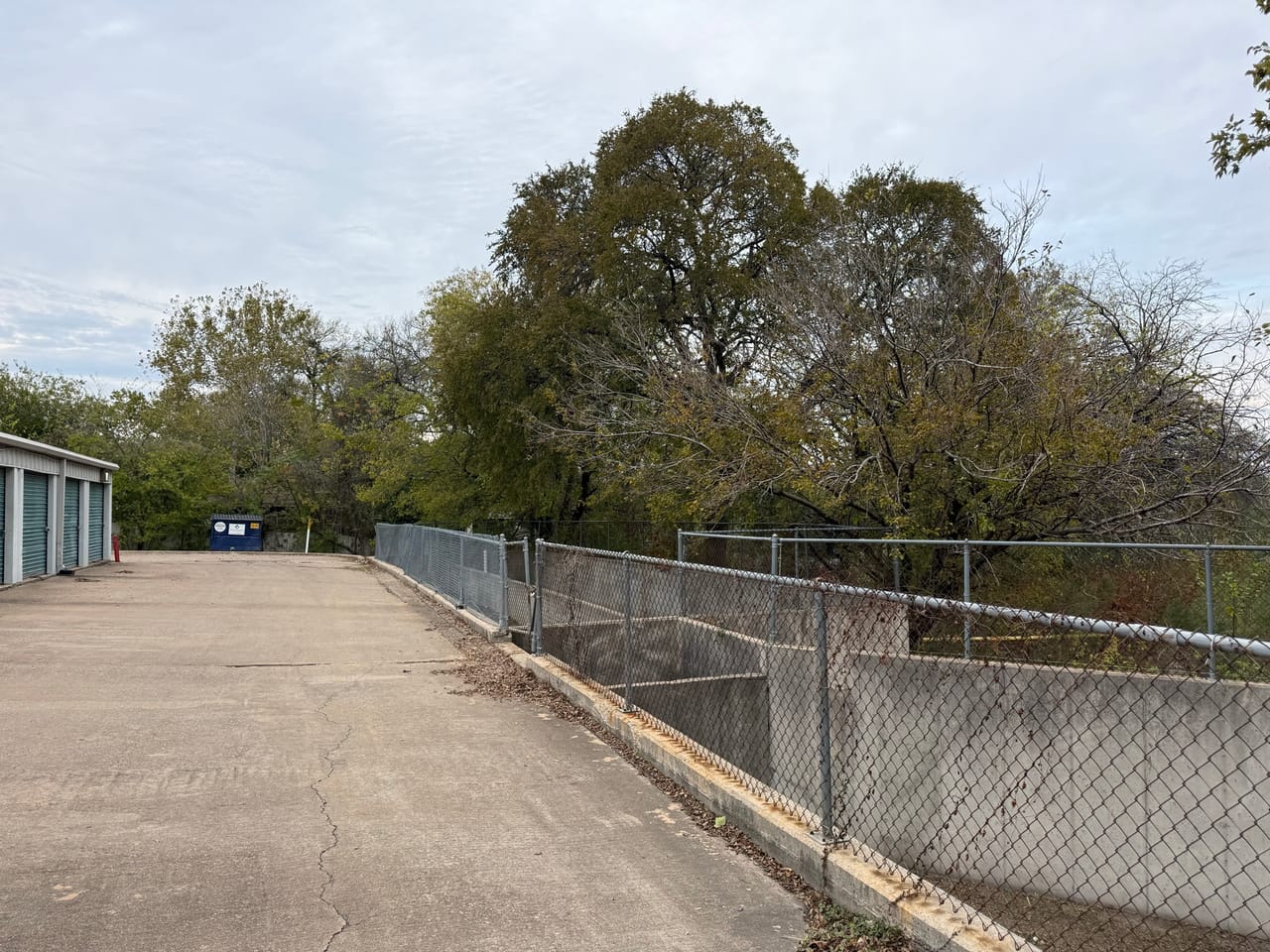 Swept concrete channel access ramp running beside a chain link fence in Leander, TX