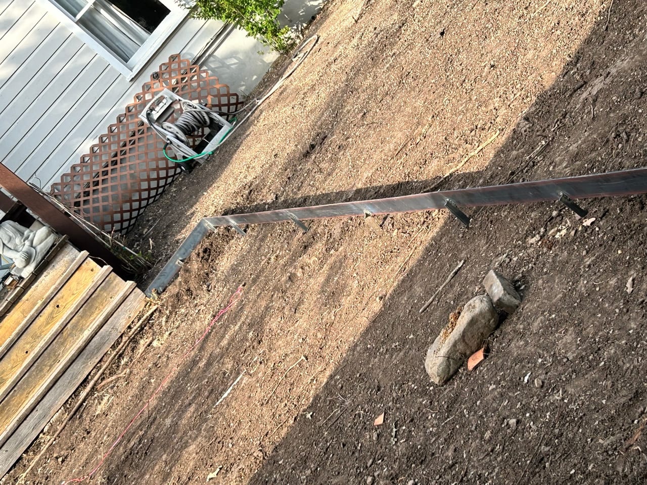 Trench dug along a fence line with steel edging and soil in Buda, TX