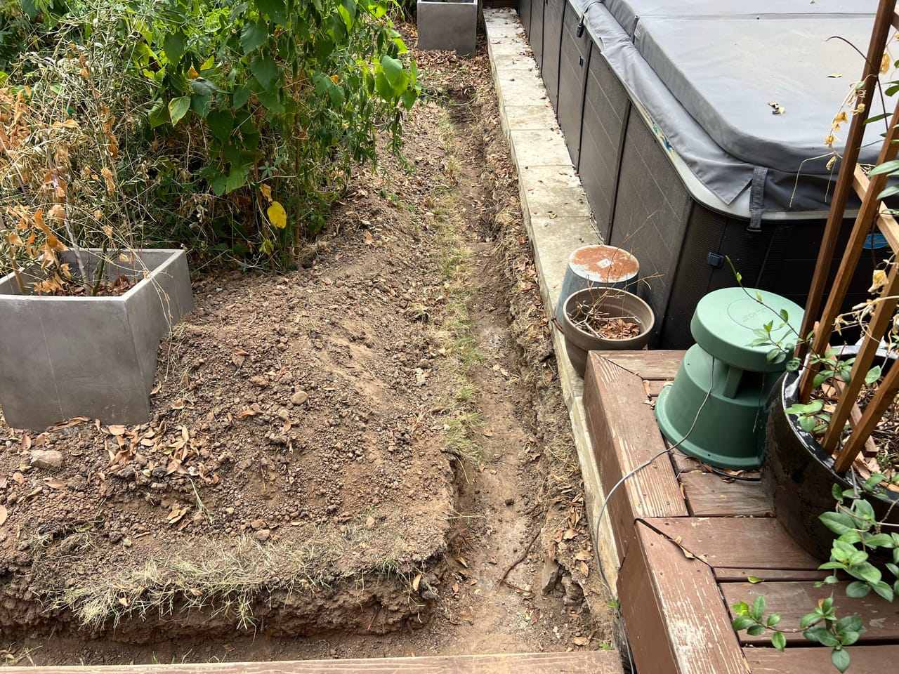 Trench excavation beside a wood deck, hot tub and valve box in Austin, TX
