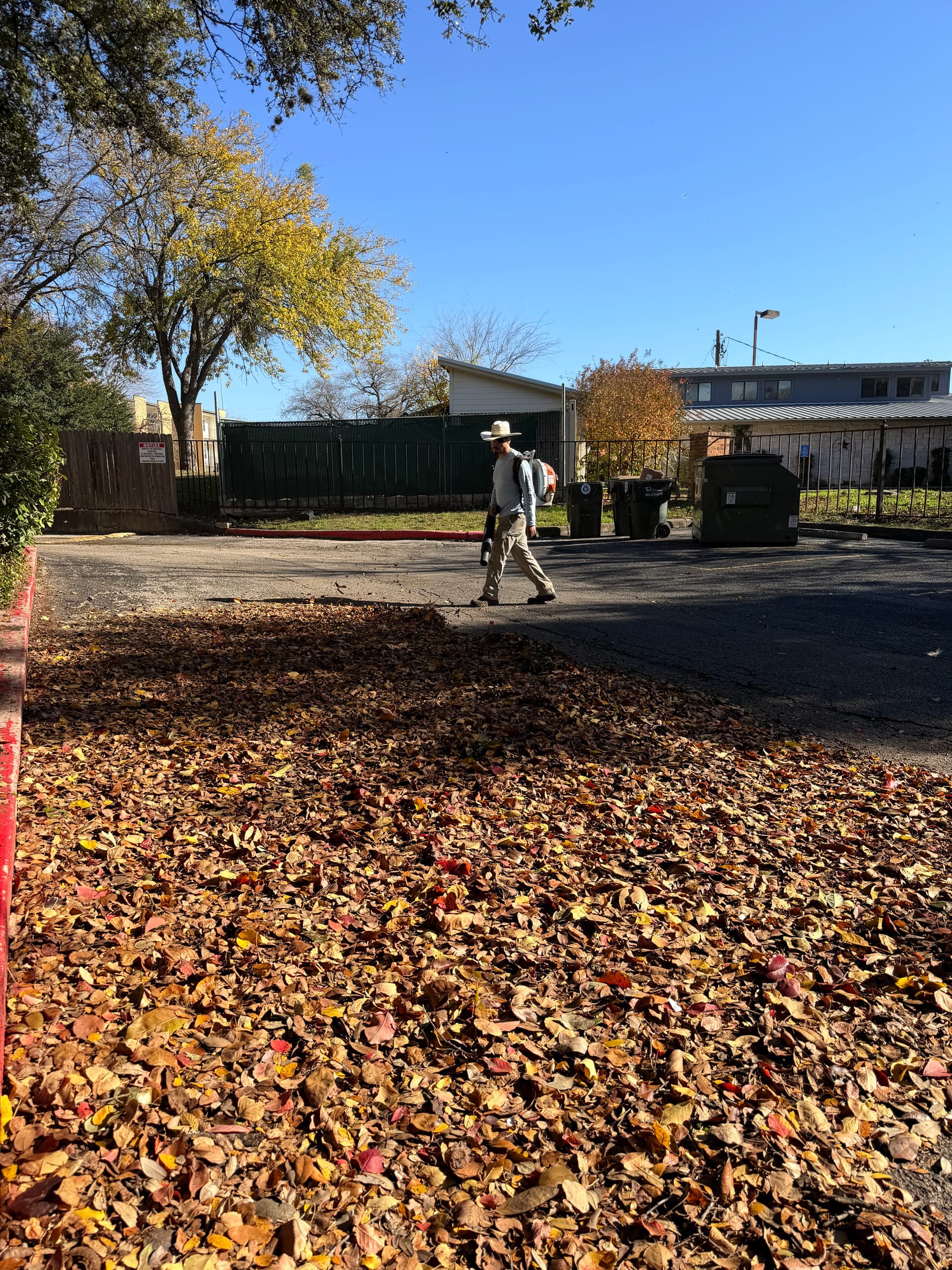Fall leaf removal and grounds cleanup in a commercial parking lot in Central Texas