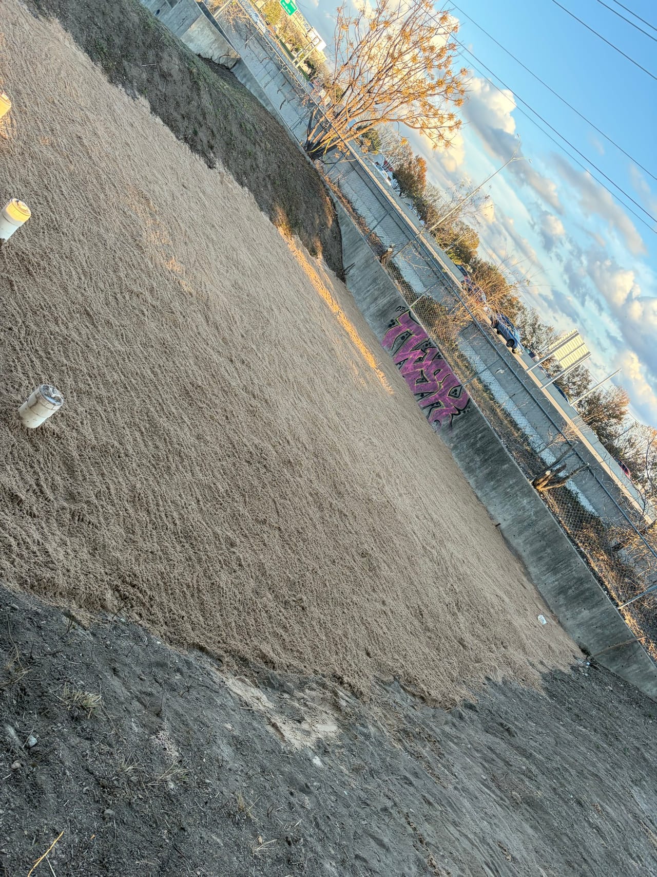 Freshly graded soil slope inside the concrete channel, awkward tilted angle in Kyle, TX