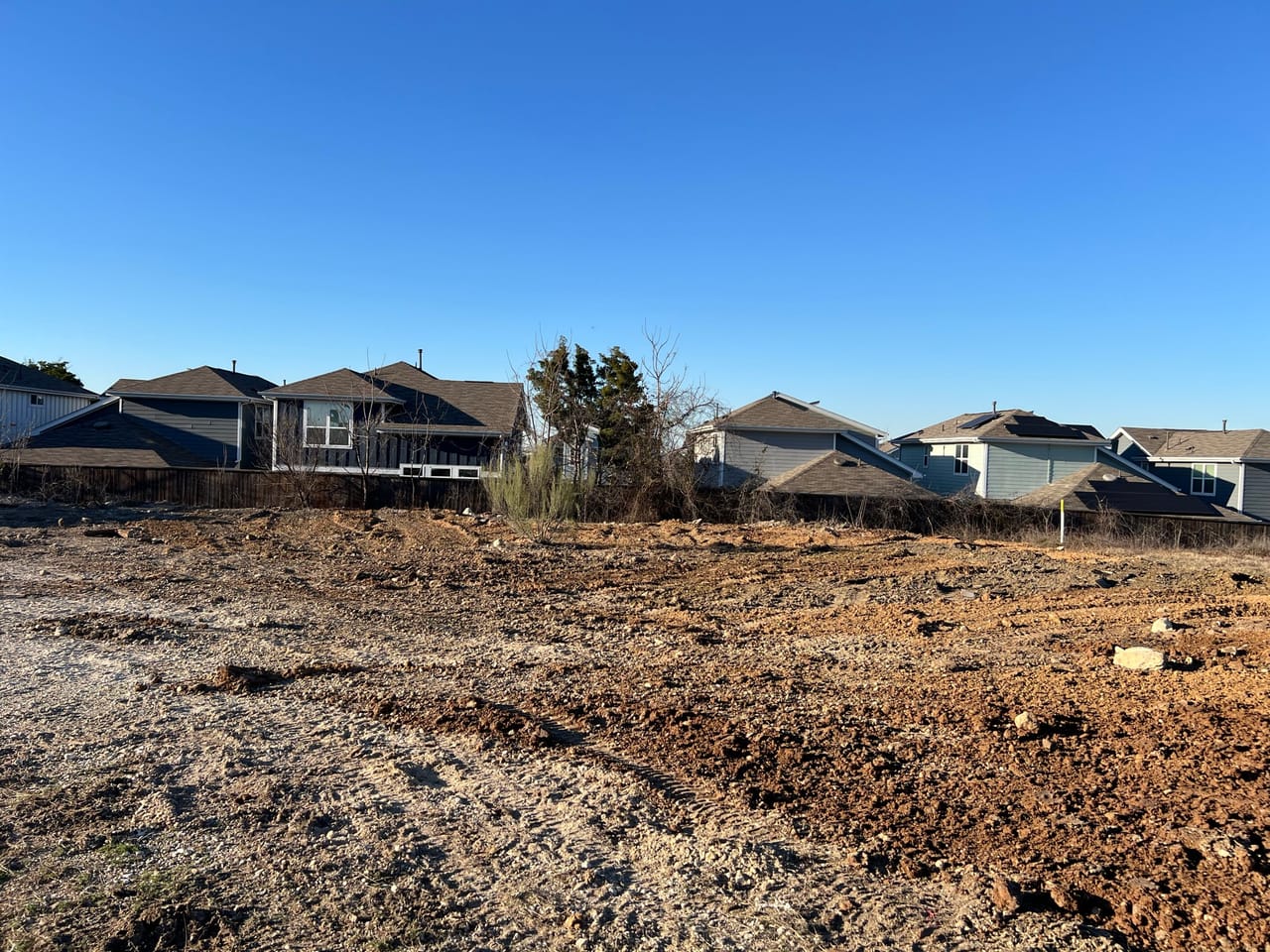Rough graded dirt pad with rooftops on the horizon in Central Texas