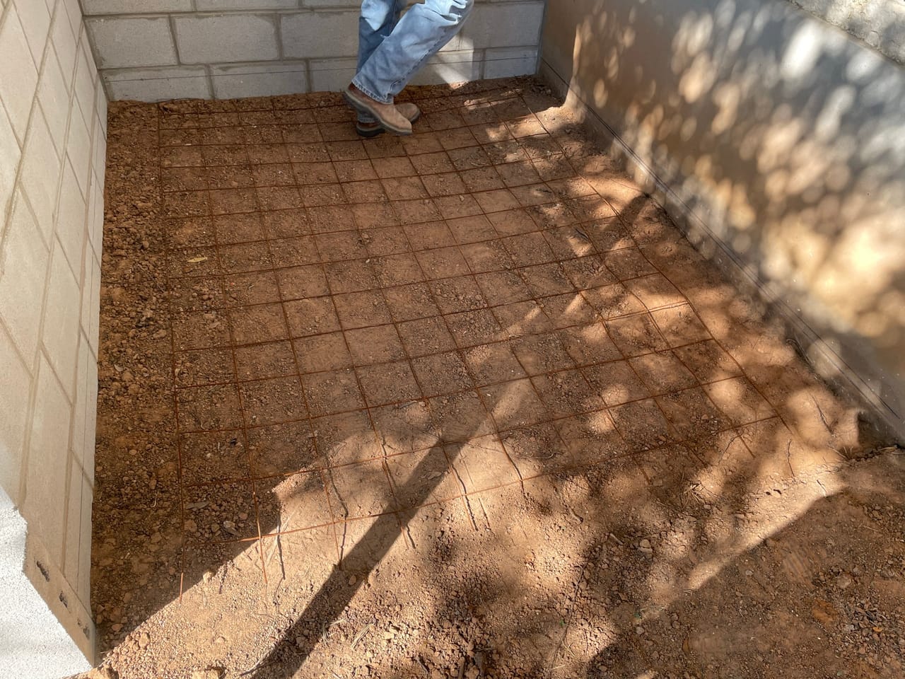 Compacted base pad inside stone walls marked out for paver layout by Corral Bros in Central Texas
