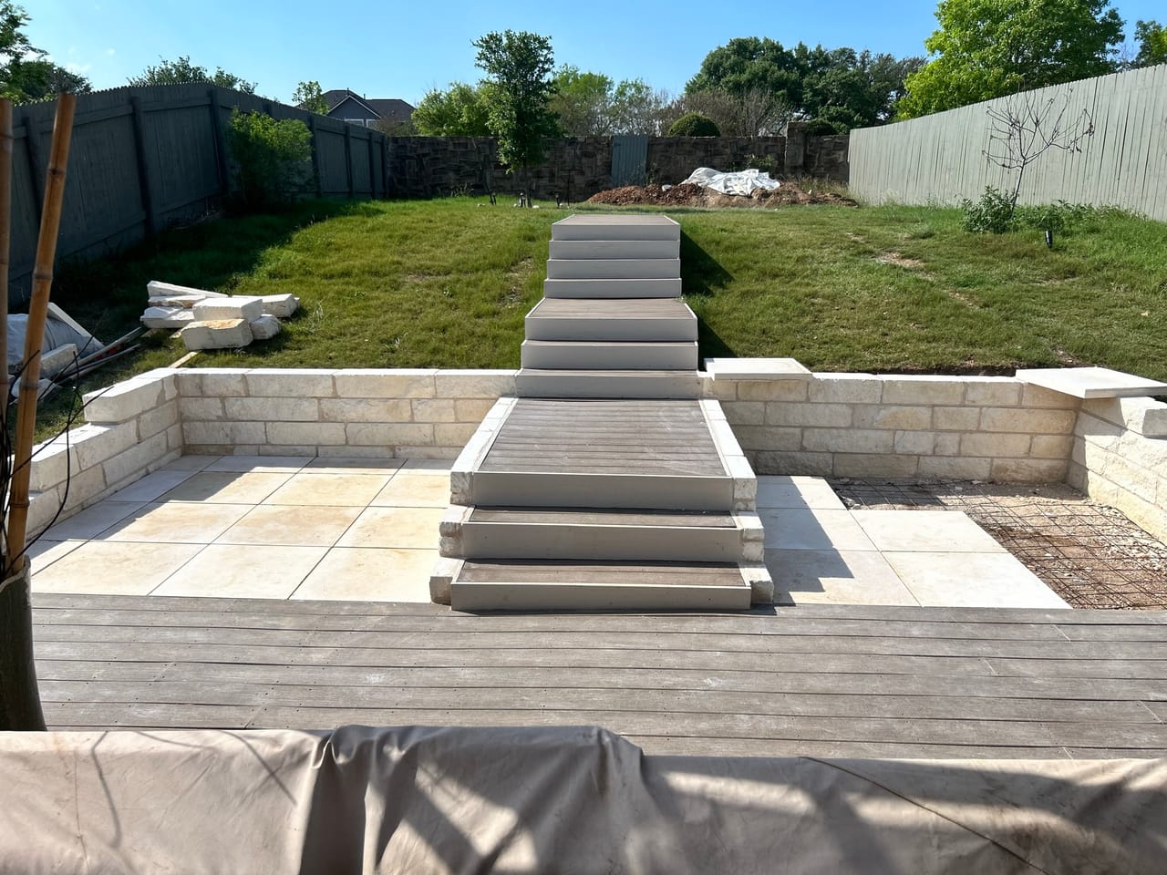 Completed backyard patio with broad stone steps rising to the lawn in Pflugerville, TX