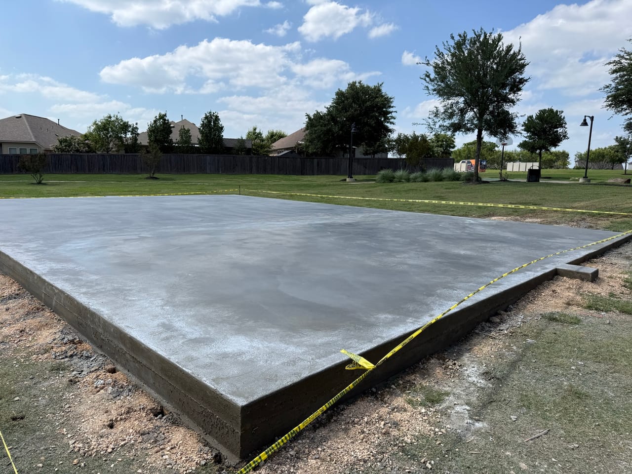 Completed concrete pad roped off with caution tape in the park in Central Texas