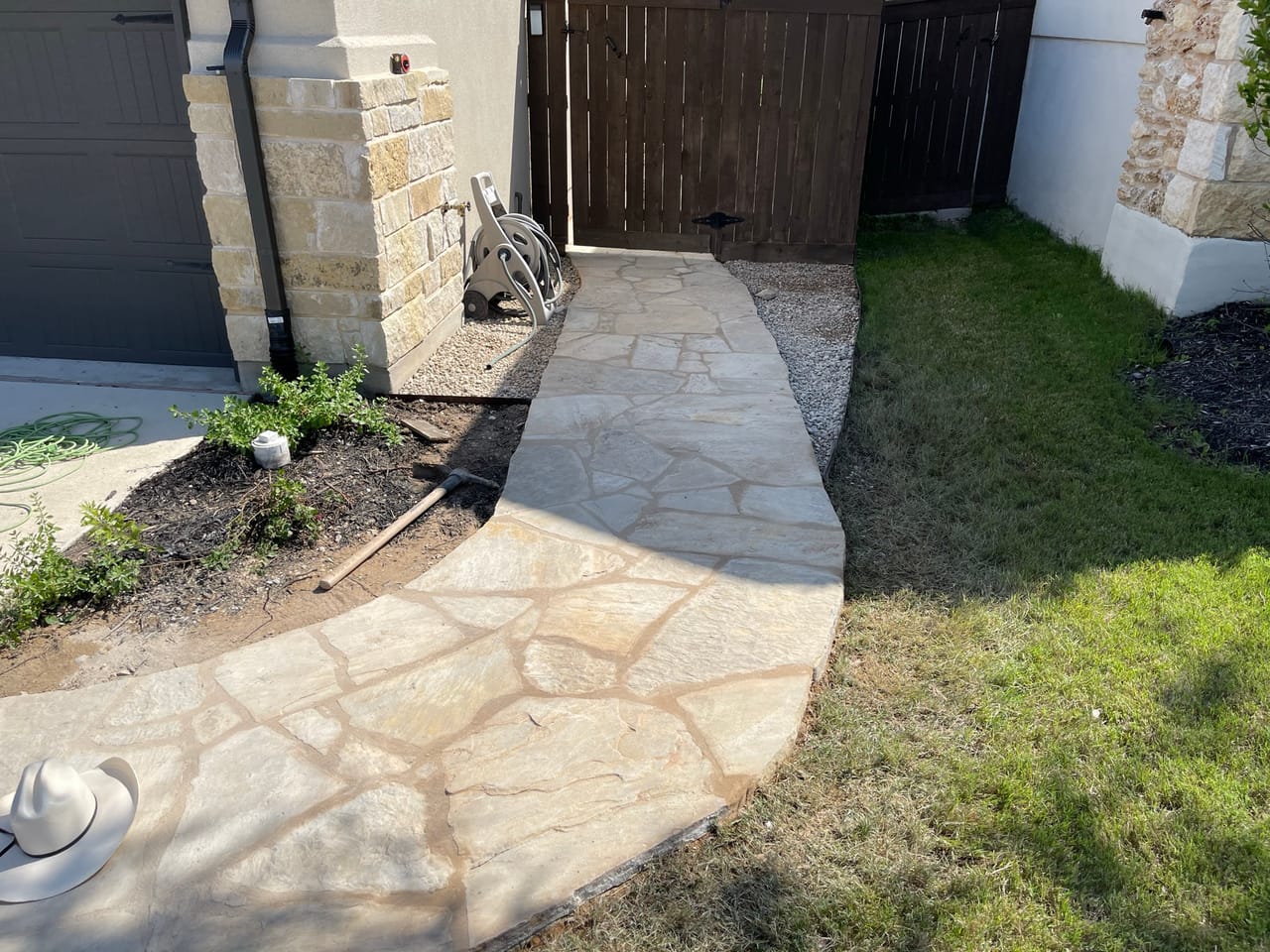 Completed flagstone walkway leading to a wood gate and stone column in Kyle, TX