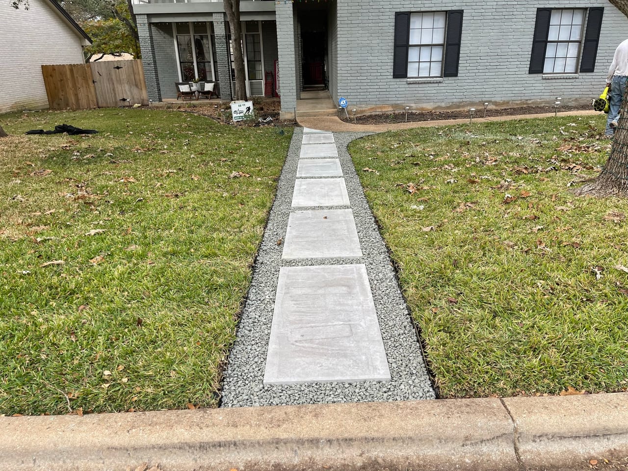 Concrete paver path with gravel border leading to a house entry in Lakeway, TX