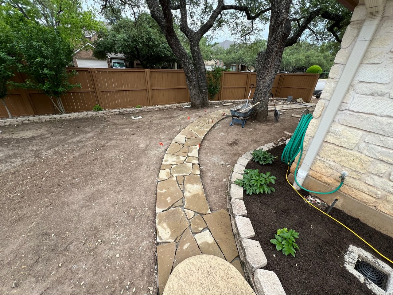 Curved stone edged flagstone path with fresh plants beside a house in Central Texas