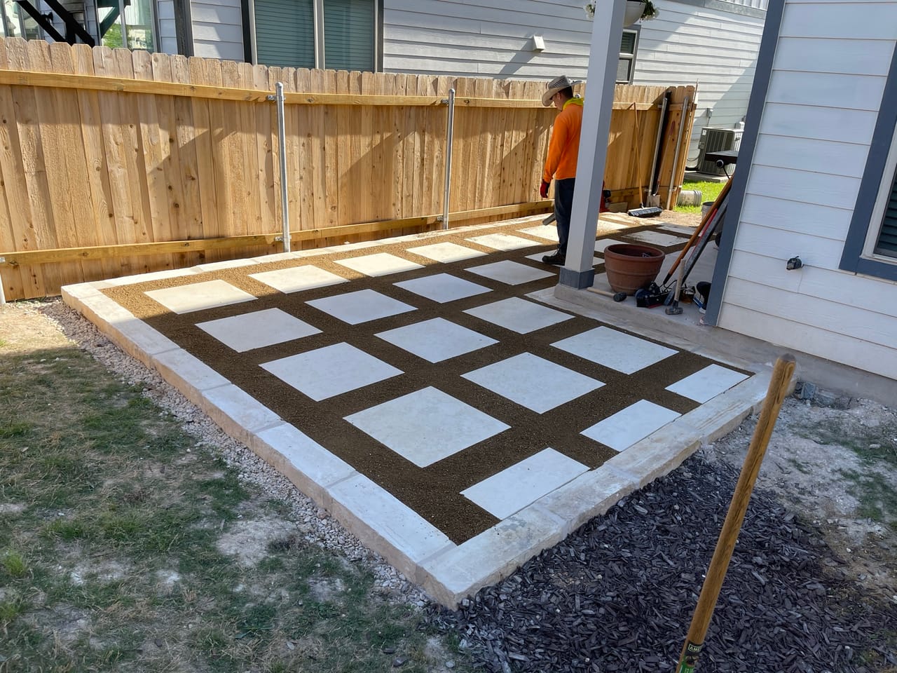 Finished checkerboard concrete paver patio with turf squares beside a house in Kyle, TX
