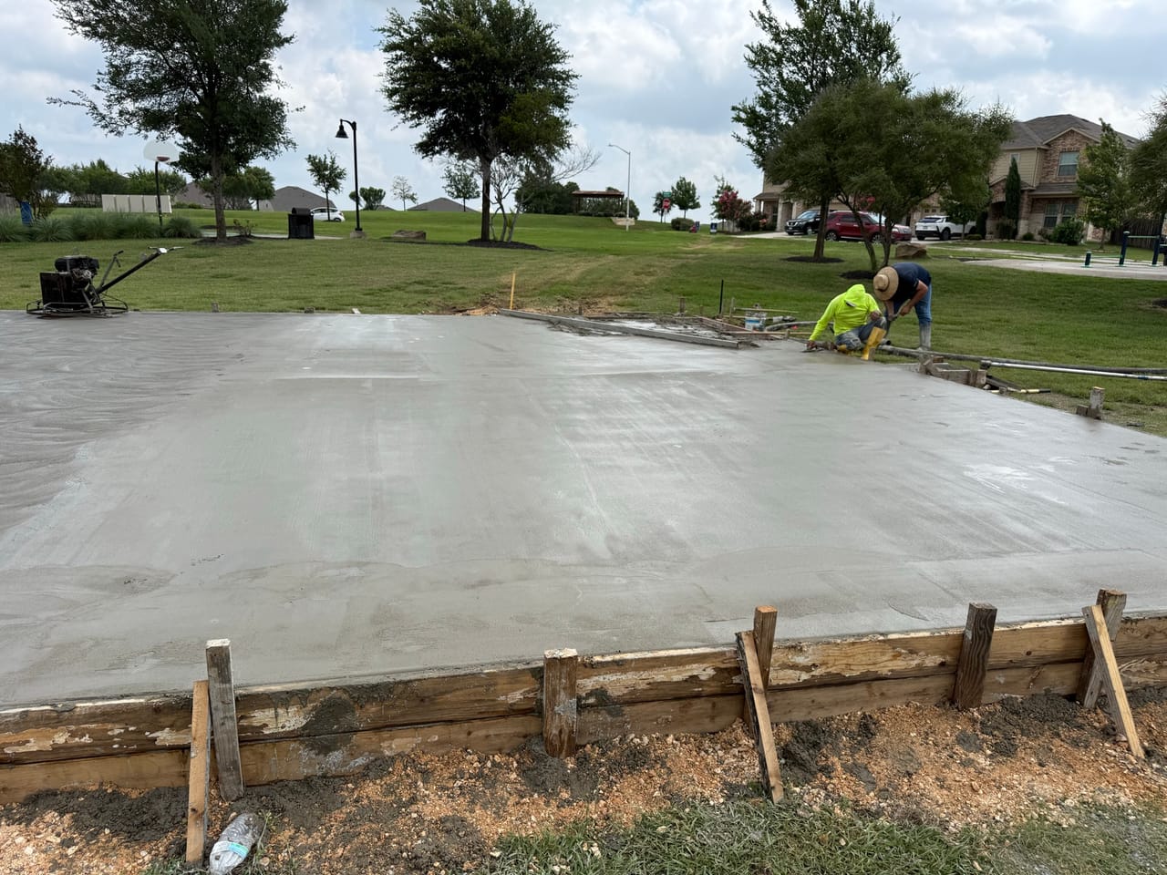 Finished concrete slab with a worker running a power trowel in Central Texas