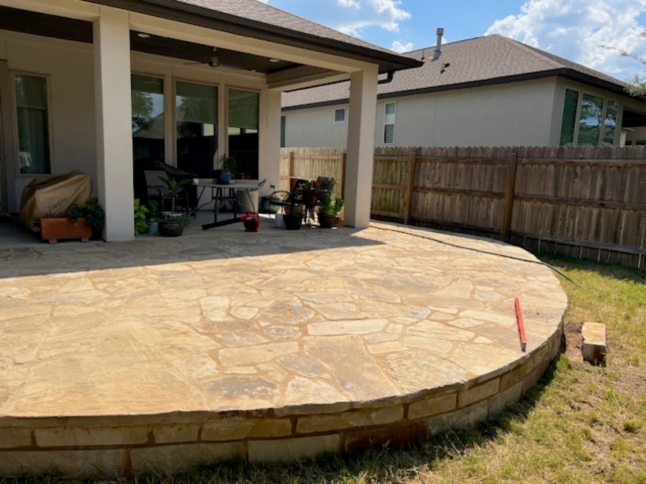 Finished curved flagstone patio with stacked limestone retaining edge in Central Texas
