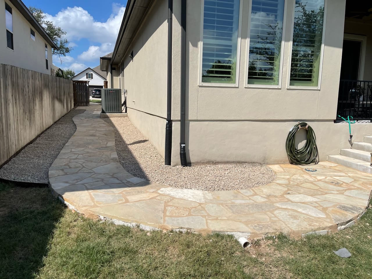 Finished flagstone path and gravel border wrapping the side of a house in Pflugerville, TX