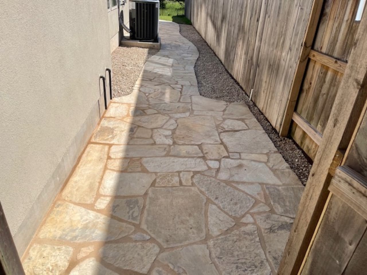 Finished flagstone side yard path running along a cedar fence in Dripping Springs, TX