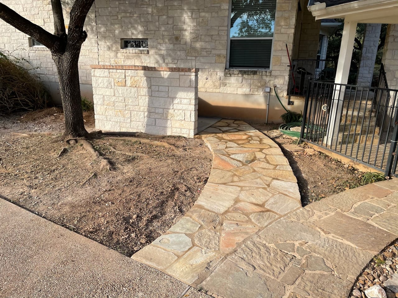 Finished flagstone walkway curving up to a capped stone wall in Georgetown, TX