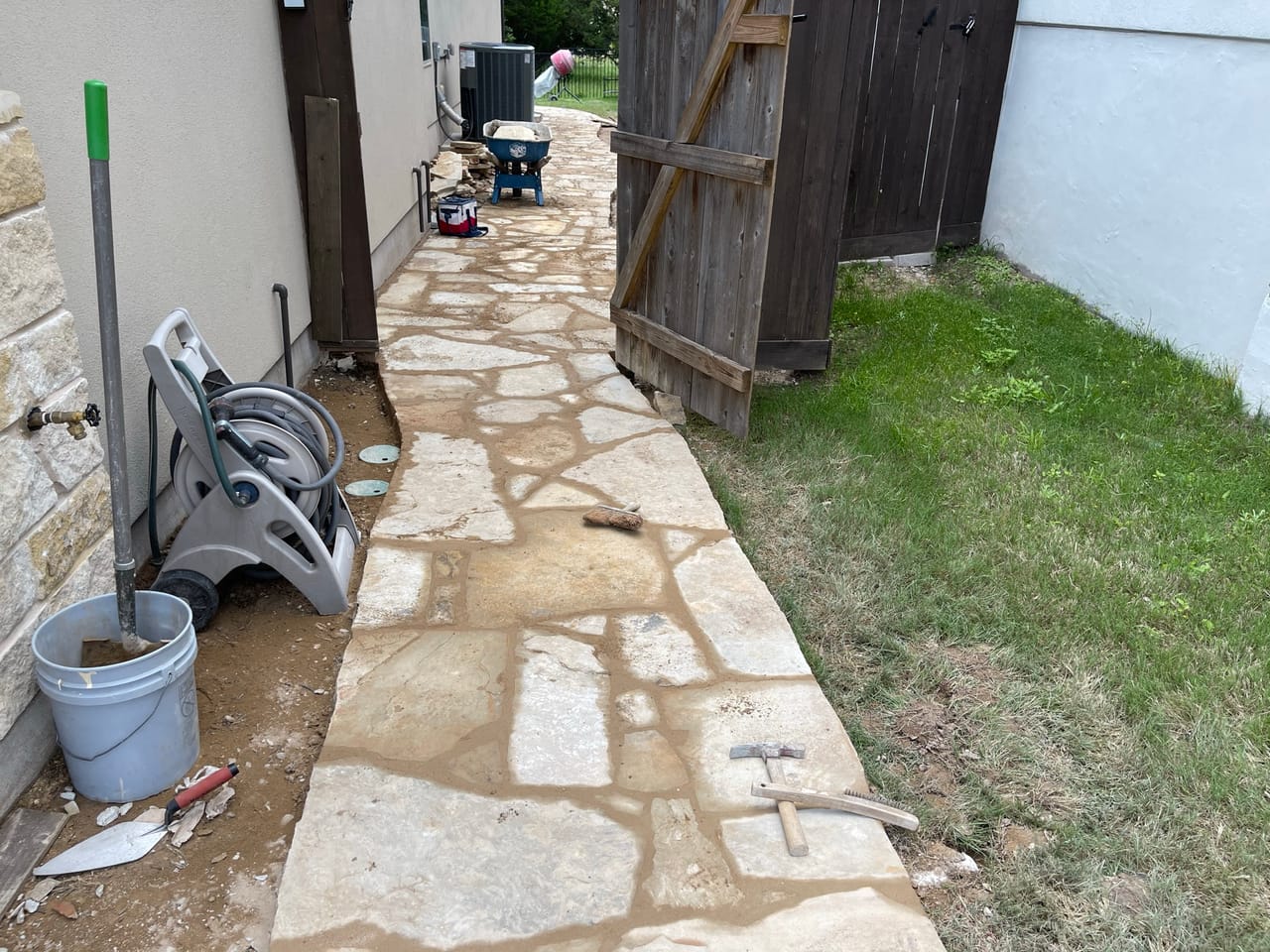 Finished flagstone walkway running beside a house next to green lawn in Central Texas