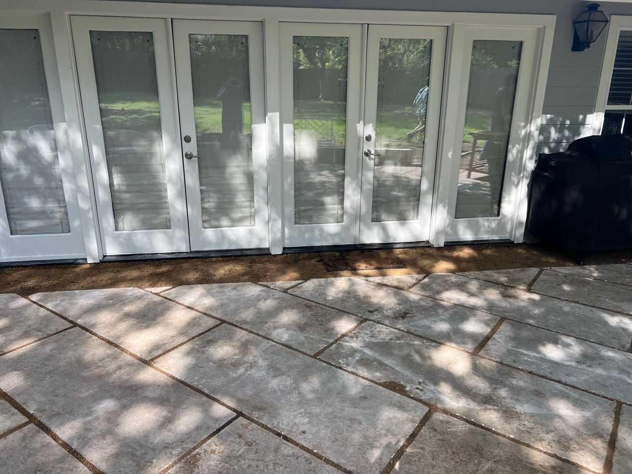 Finished large format stone patio in front of white french doors in Taylor, TX