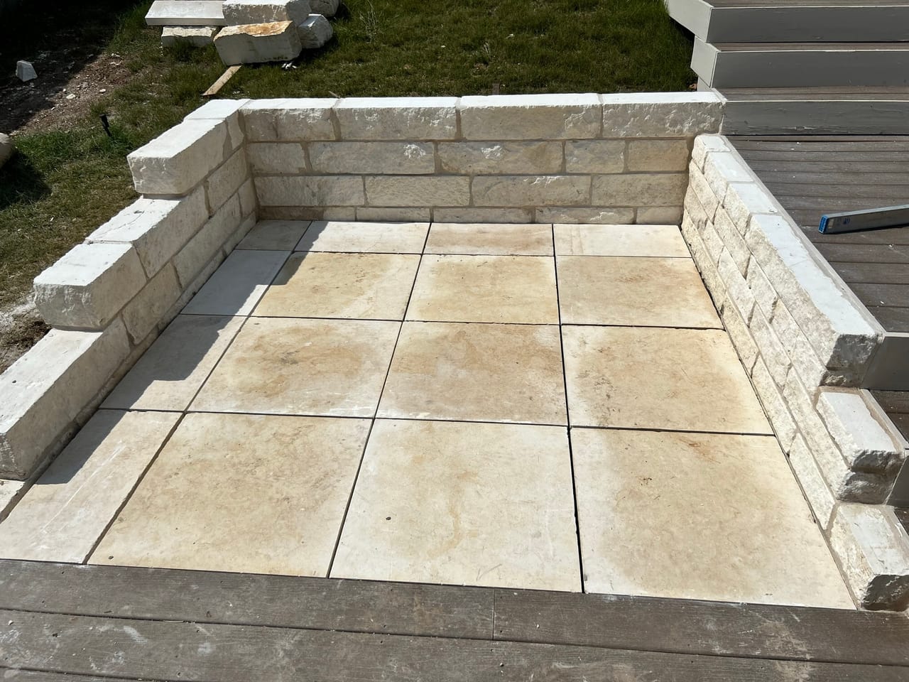 Finished paver patio enclosed by limestone seat walls in a backyard in Leander, TX