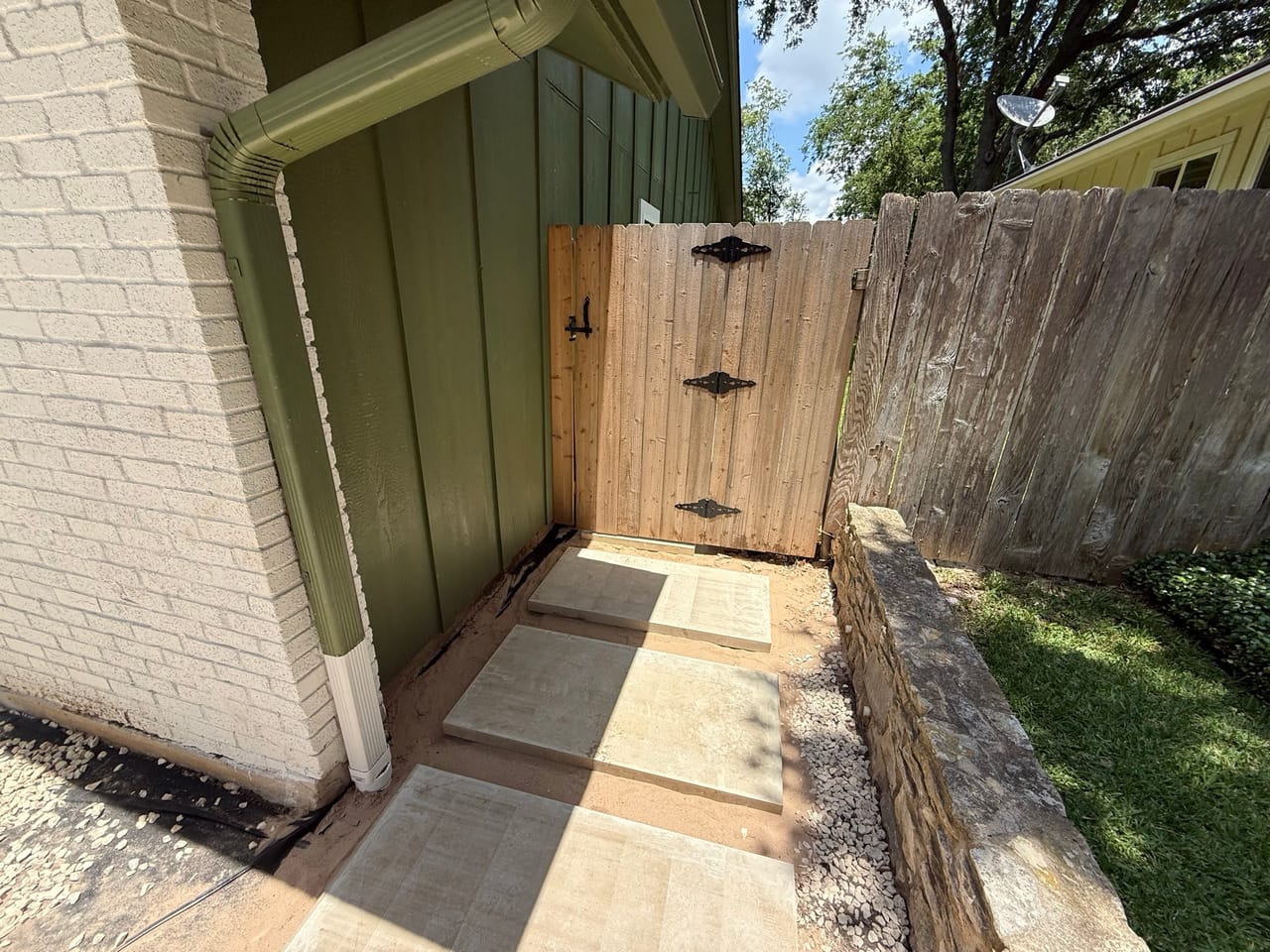 Flagstone path along the side of a house leading to a wood gate in Central Texas