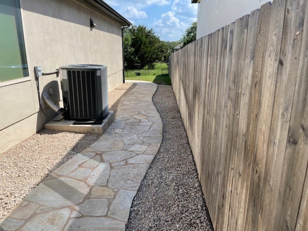 Flagstone path with gravel border passing an air conditioner unit in Lago Vista, TX