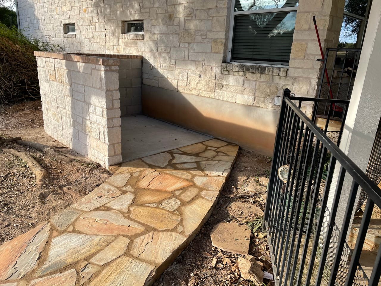Flagstone path leading to stone steps and iron rail at house in Round Rock, TX
