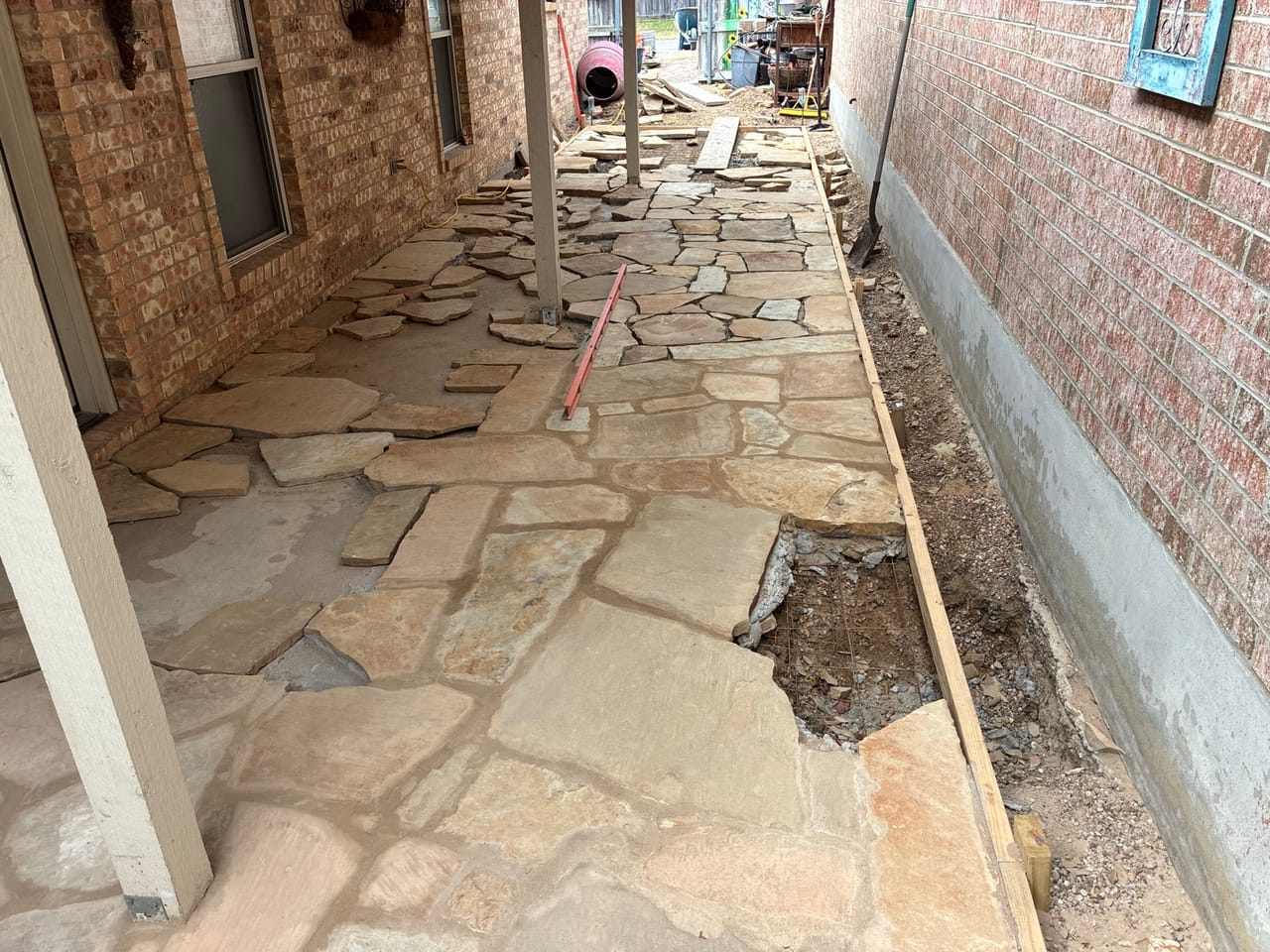 Flagstone path in progress beside a house with a guide string line by Corral Bros in Central Texas